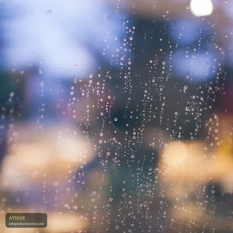 Raindrops on a window pane with soft, blurred lights behind