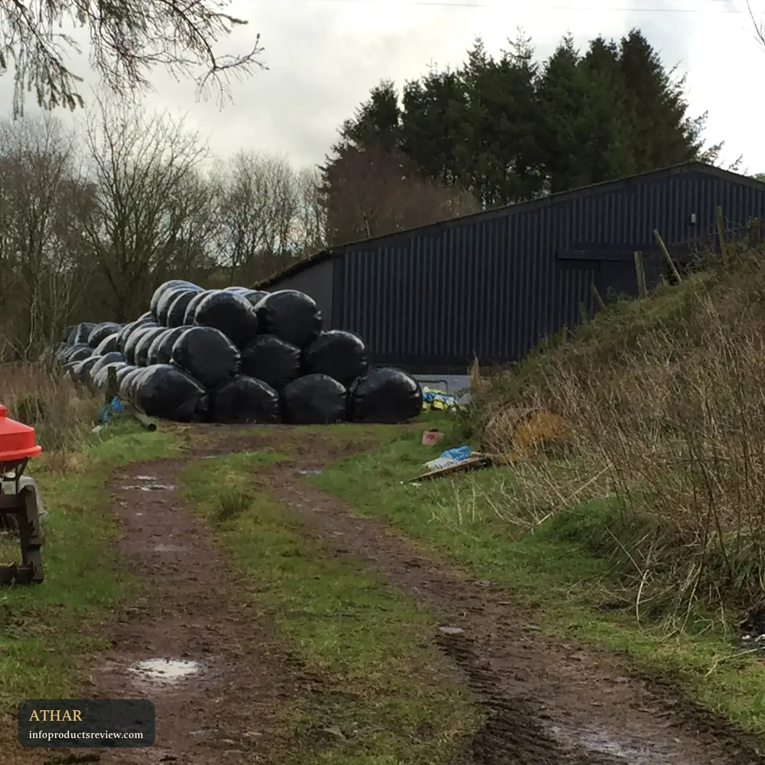 A rural barn with wrapped hay bales in front